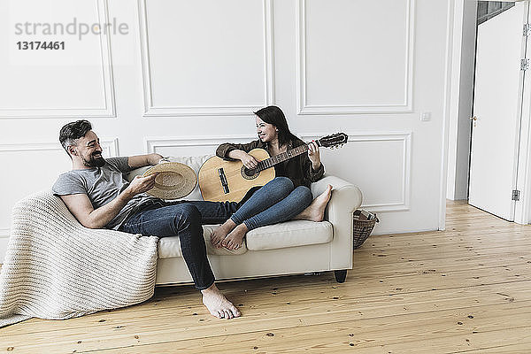 Entspanntes Paar sitzt auf Couch  Frau spielt zu Hause Gitarre