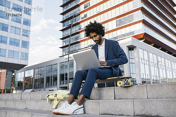 Spanien  Barcelona  junger Geschäftsmann sitzt draußen in der Stadt und arbeitet am Laptop