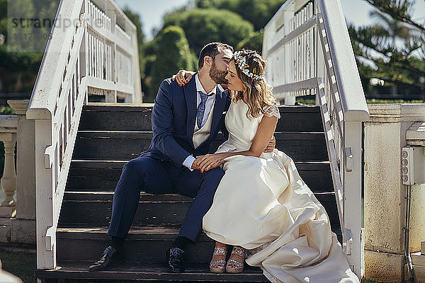 Brautpaar sitzt auf einer Treppe und genießt ihren Hochzeitstag