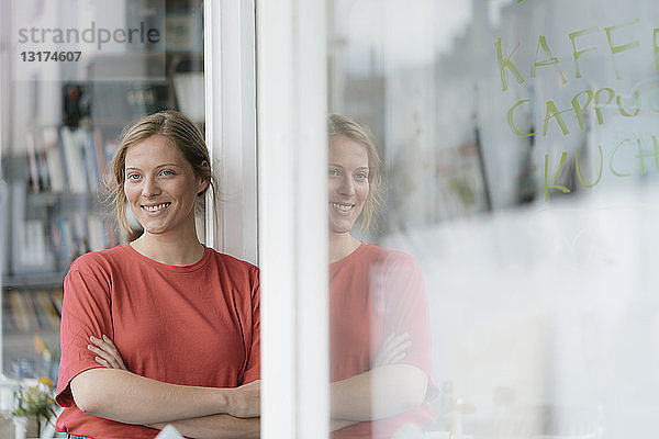 Porträt einer lächelnden jungen Frau vor französischer Tür in einem Café