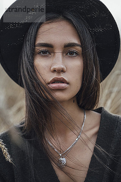Porträt einer modischen jungen Frau mit schwarzem Hut