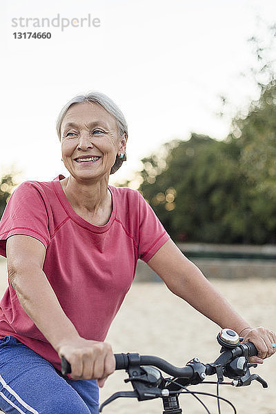 Porträt einer lächelnden älteren Frau beim Fahrradfahren