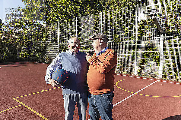 Zwei fitte Senioren amüsieren sich auf einem Basketballfeld