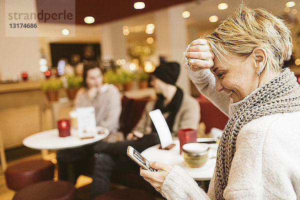 Junge glückliche Frau benutzt Smartphone in einem Cafe