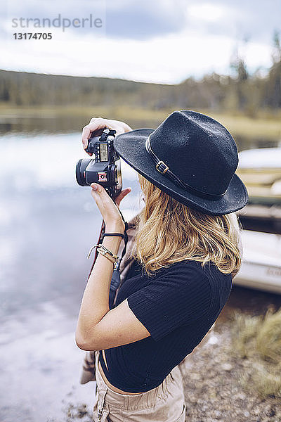 Schweden  Lappland  junge Frau mit schwarzem Hut beim Fotografieren mit Kamera