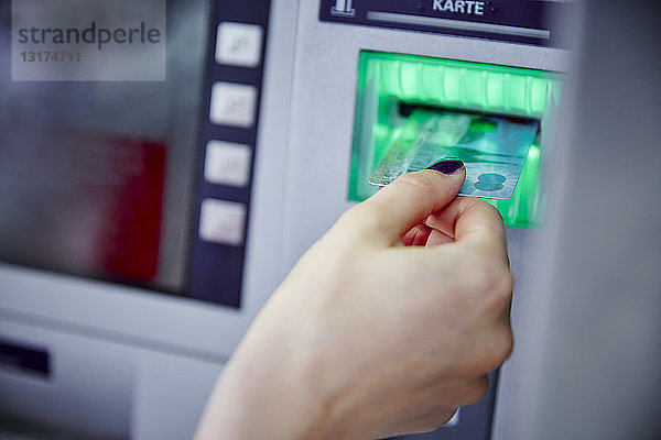 Nahaufnahme einer Frau  die eine Karte in den Schlitz eines Geldautomaten steckt
