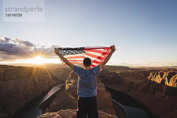 USA  Arizona  Colorado River  Horseshoe Bend  junger Mann auf Aussichtspunkt mit amerikanischer Flagge