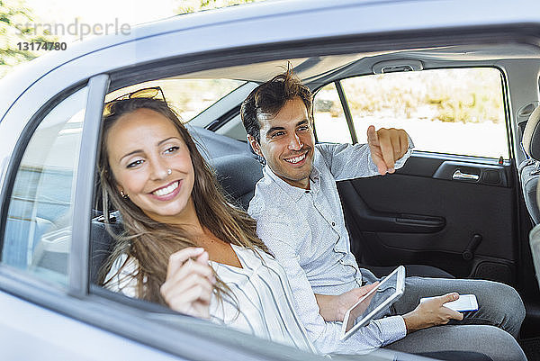 Lächelndes Paar auf dem Rücksitz eines Autos  das aus dem Fenster schaut