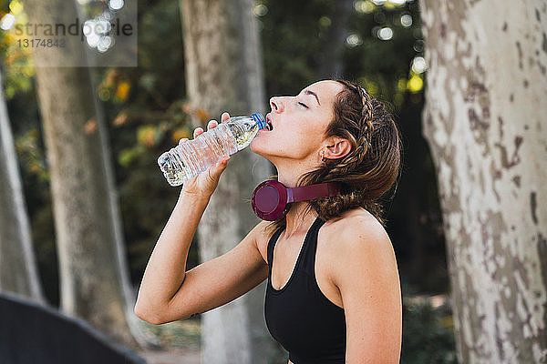 Fitte junge Frau macht eine Pause  trinkt Wasser