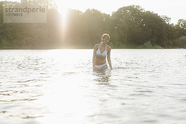 Porträt einer glücklichen Frau im Bikini in einem See