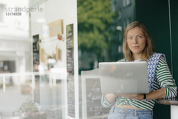 Porträt einer jungen Frau mit Laptop in einem Cafe