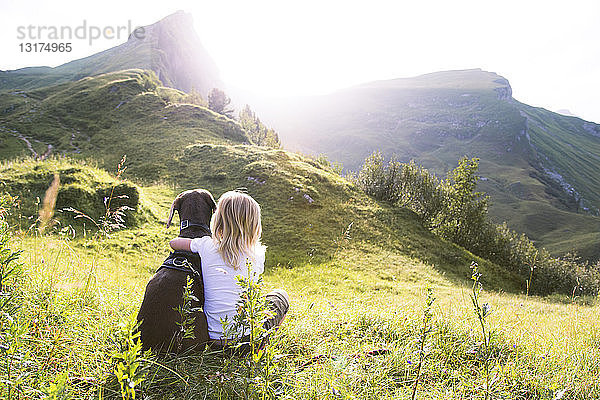 Österreich  Südtirol  junges Mädchen sitzt mit Hund auf der Wiese