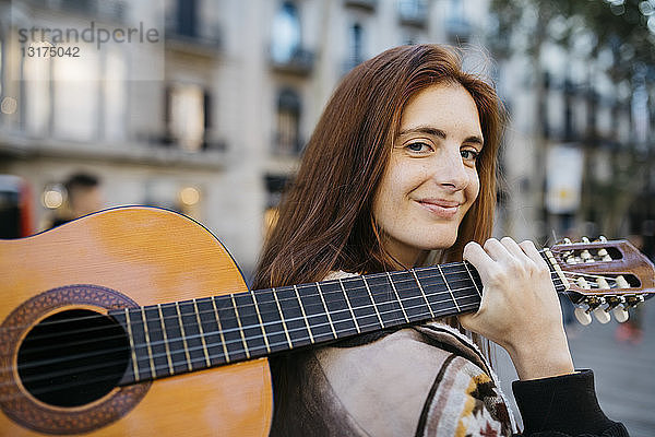Rothaarige Frau mit Gitarre in der Stadt