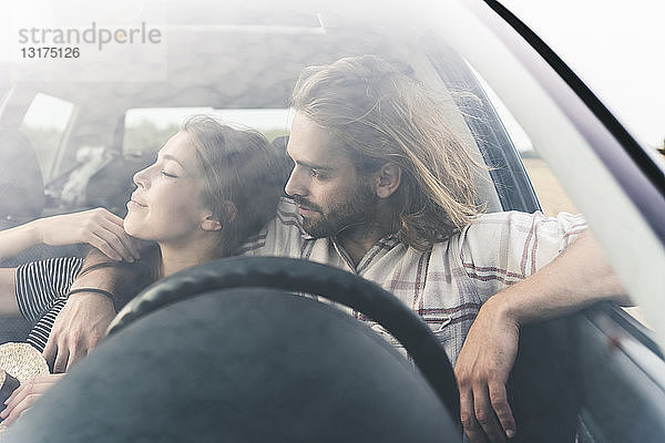 Zärtliches junges Paar in einem Auto