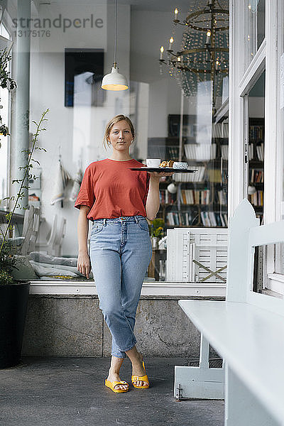Porträt einer jungen Frau  die in einem Café Kaffee und Kuchen serviert
