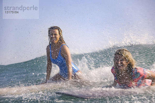 Indonesien  Bali  Strand von Batubolong  junge Surferinnen an Bord  Spritzwasser