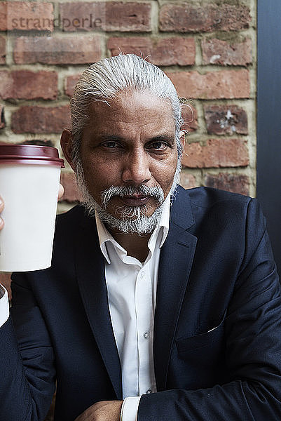 Porträt eines bärtigen Senior-Geschäftsmannes mit Kaffee zum Mitnehmen