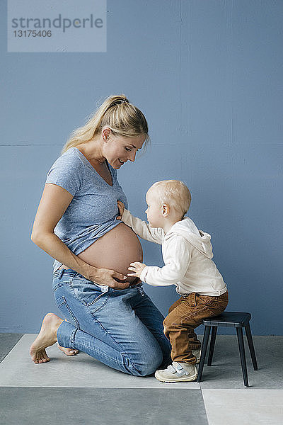 Kleinkind untersucht den Bauch der schwangeren Mutter