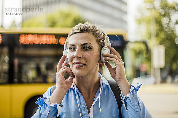 Porträt einer lächelnden Frau in der Stadt mit Kopfhörern