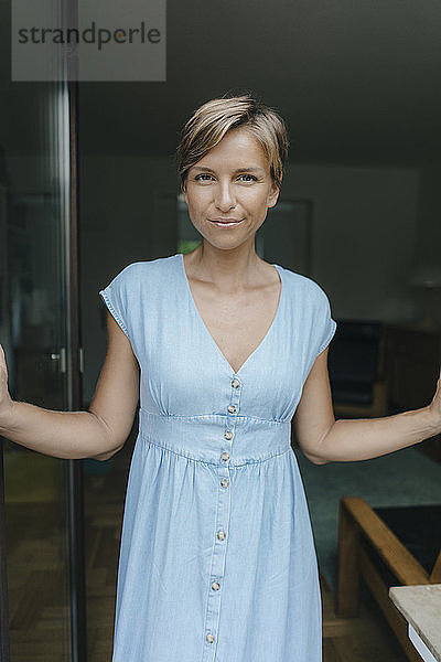 Porträt einer selbstbewussten Frau am französischen Fenster stehend