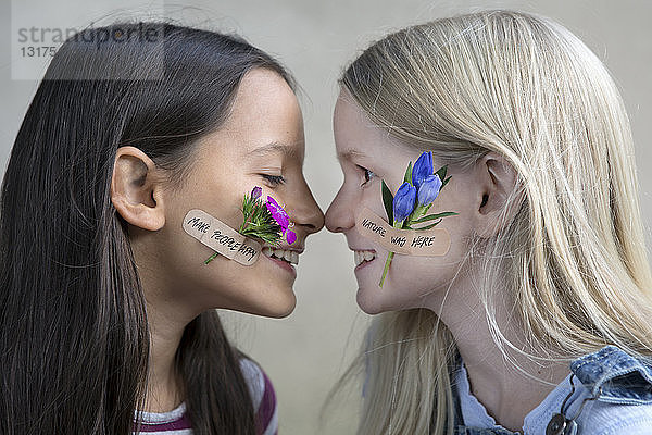 Profile von zwei lächelnden Mädchen mit Blumenköpfen auf den Wangen