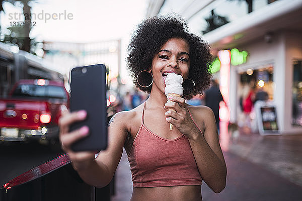 USA  Nevada  Las Vegas  glückliche junge Frau beim Eisessen in der Stadt  die ein Selfie nimmt