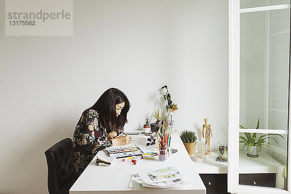 Illustrator am Schreibtisch in einem Atelier mit digitalem Tablett zum Malen