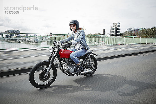 Deutschland  Köln  junge Frau mit Motorrad auf der Brücke