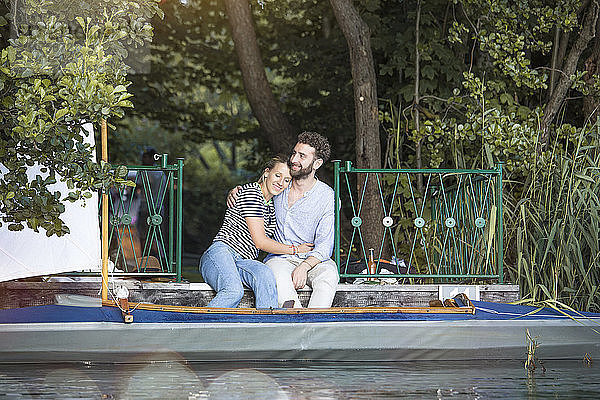 Glückliches junges Paar mit Kanu auf einem Steg sitzend