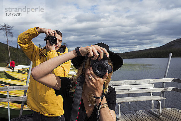 Finnland  Lappland  Mann und Frau beim Fotografieren auf einem Steg an einem See