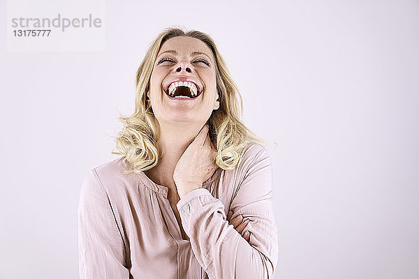 Porträt einer lachenden blonden Frau  die sich zurücklehnt