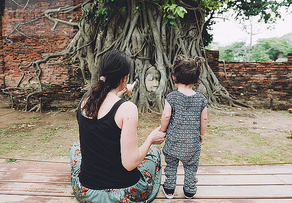 Thailand  Ayutthaya  Mutter und Tochter besuchen den Buddhakopf zwischen Baumwurzeln im Wat Mahathat