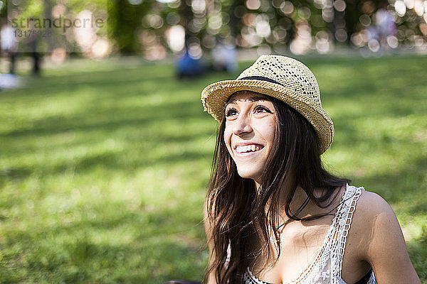 Porträt einer glücklichen jungen Frau in einem Park  die etwas beobachtet