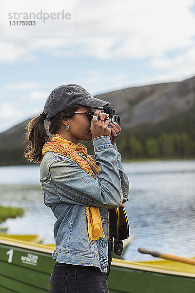 Finnland  Lappland  Frau beim Fotografieren mit einer Kamera am Seeufer