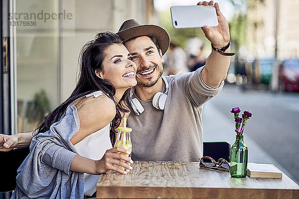 Glückliches junges Paar beim Selfie in einem Café im Freien