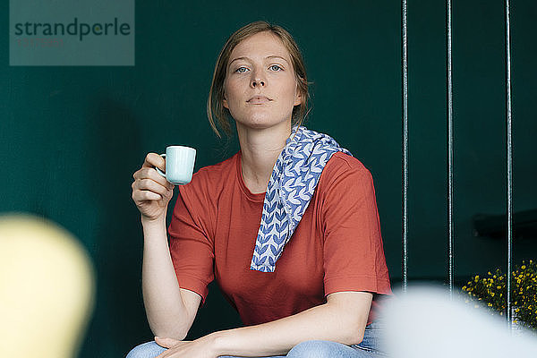 Junge Frau sitzt in einem Café und hält eine Espressotasse