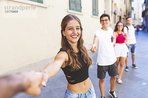 Eine Gruppe von Freunden geht in der Stadt spazieren und hält sich an den Händen