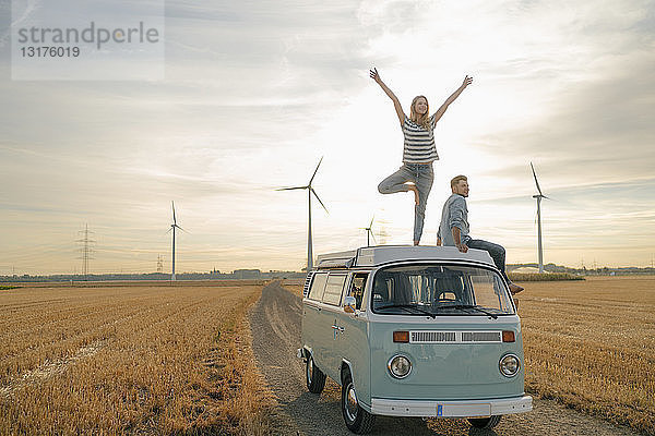 Junges Paar auf dem Dach eines Wohnmobils in ländlicher Landschaft