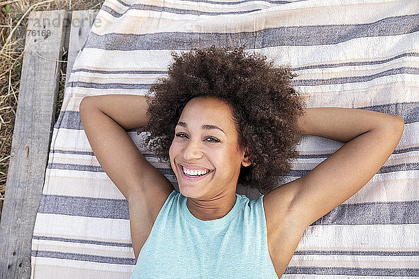 Porträt einer glücklichen Frau  die im Freien auf einer Decke liegt