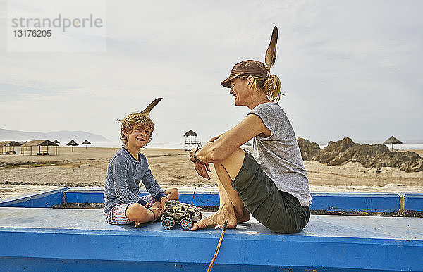 Chile  Arica  glückliche Mutter sitzt mit ihrem Sohn an einer Mauer am Strand