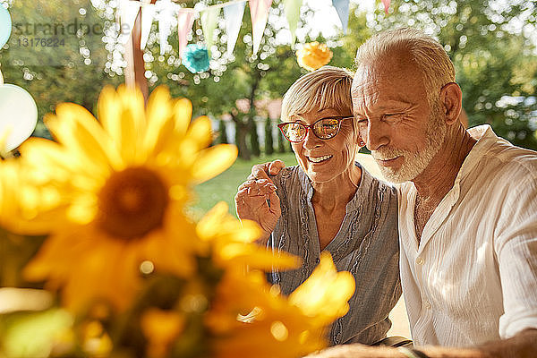 Glückliches älteres Ehepaar umarmt sich auf einer Gartenparty