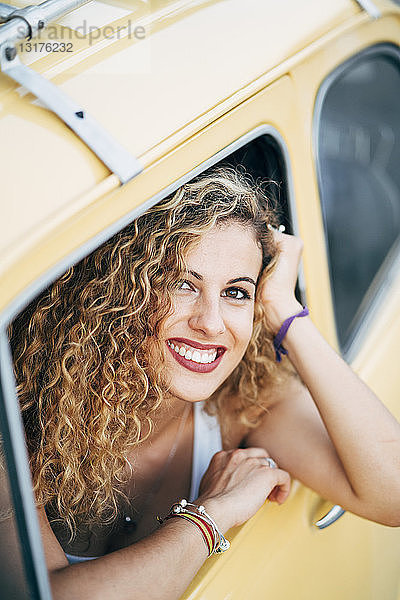 Porträt einer glücklichen blonden Frau  die aus dem Fenster eines Oldtimers schaut