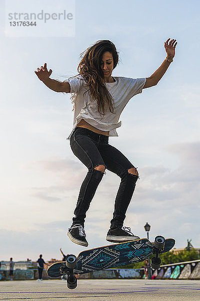 Junge Frau bei einem Skateboardtrick in der Stadt