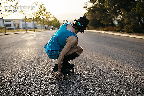Mann fährt Skateboard auf leeren Rasenflächen bei Sonnenuntergang
