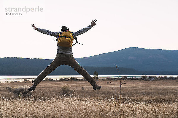 USA  Nordkalifornien  Rückansicht eines jungen Mannes auf einer Wanderung  der in der Nähe des Lassen Volcanic National Park springt