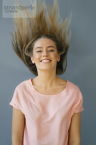 Porträt einer lächelnden jungen Frau  die ihr Haar wirft