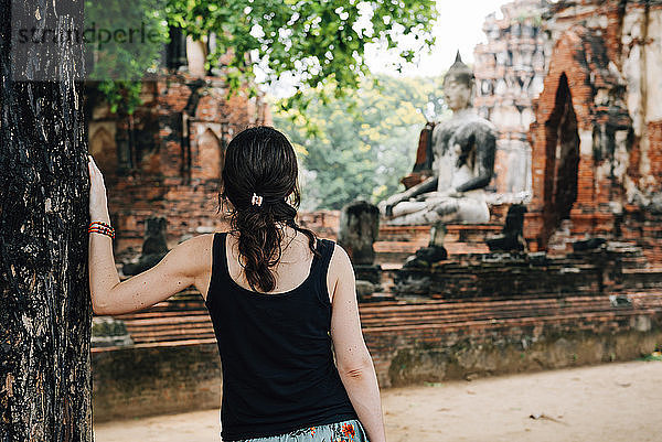 Thailand  Ayutthaya  Frau betrachtet eine Buddhastatue im Wat Mahathat