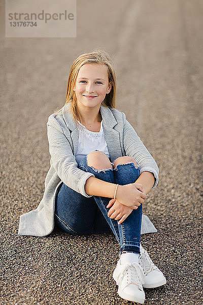 Porträt eines lächelnden Mädchens am Boden sitzend