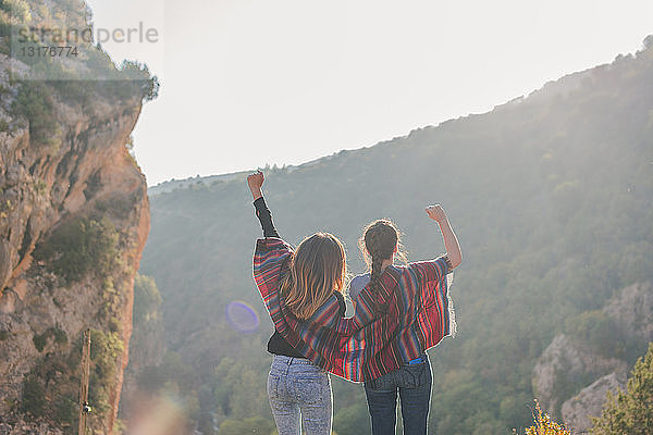 Spanien  Alquezar  Rückansicht von zwei jungen Frauen auf einer Wanderung  die jubeln