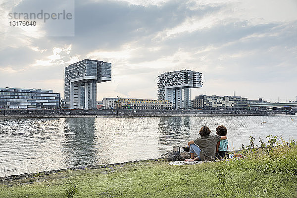 Deutschland  Köln  Paar entspannt am Flussufer bei Sonnenuntergang